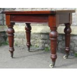 A Victorian mahogany rectangular fold over top table raised on turned supports with brass caps and