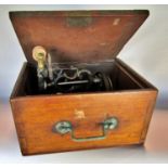 A small un-marked sewing machine housed in a mahogany carry case.