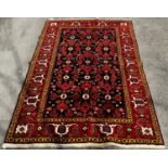 A fine brightly coloured Shirvan carpet with a central panel geometric stylised flowers on a dark