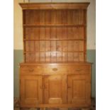 A stripped and waxed pine farmhouse kitchen dresser, the base enclosed by three rectangular