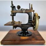 A miniature Singer Sewing Machine, on a wooden plinth, 20cm high x 19cm wide (inc the plinth)