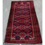 A Kazak carpet with repeating stepped medallions in reds and blues, 172cm x 92cm approx.