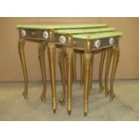 A nest of three graduated simulated onyx top occasional tables, with gilt finish, applied Limoges