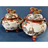 A pair of large Satsuma lidded urns standing on three legs, decorated with panels of characters,