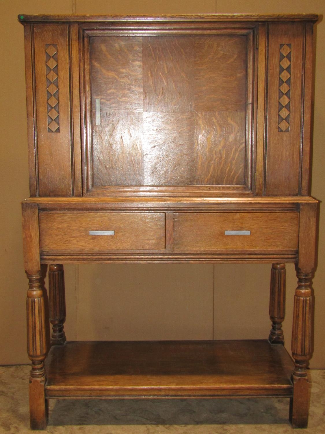 An early 20th century oak freestanding side cupboard enclosed by a central panelled door, with