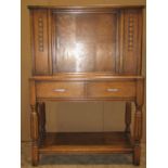 An early 20th century oak freestanding side cupboard enclosed by a central panelled door, with