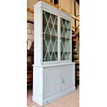A painted library bookcase, the lower section enclosed by two panelled doors, the upper section by