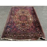 An old Persian carpet with a central floral medallion on a field of flowers, 104cm x 74cm approx.