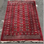 A Turkoman carpet with a central panel od small elephant foot gul on predominantly red ground, 185cm