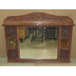 An Arts & Crafts overmantle mirror, the oak frame with carved pomegranate and berry detail, flanking