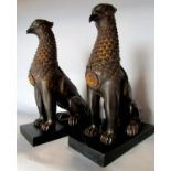 A pair of wingless Griffins, in a bronze effect finish, raised on slate plinths. 27cm tall