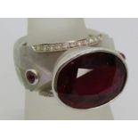 Unusual 18k white gold cocktail ring set with a large garnet to centre, flanked by two cabochon