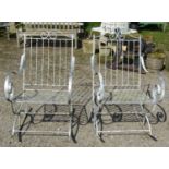 A pair of decorative painted ironwork garden rocking chairs with open scrolled arms and lattice