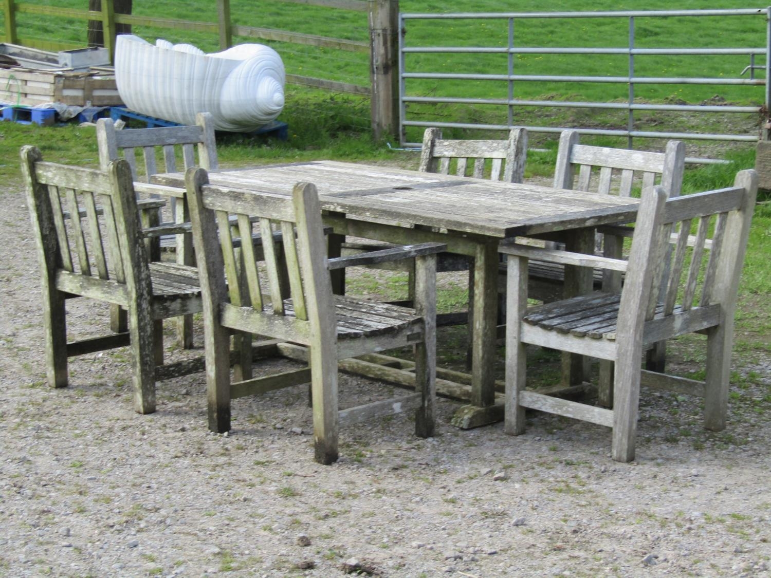 A weathered Gloster teak garden table with rectangular slatted panelled top, raised on rectangular