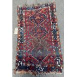 A small old Kazak rug with three interlocking central lozenge, partially worn in places, 120cm x