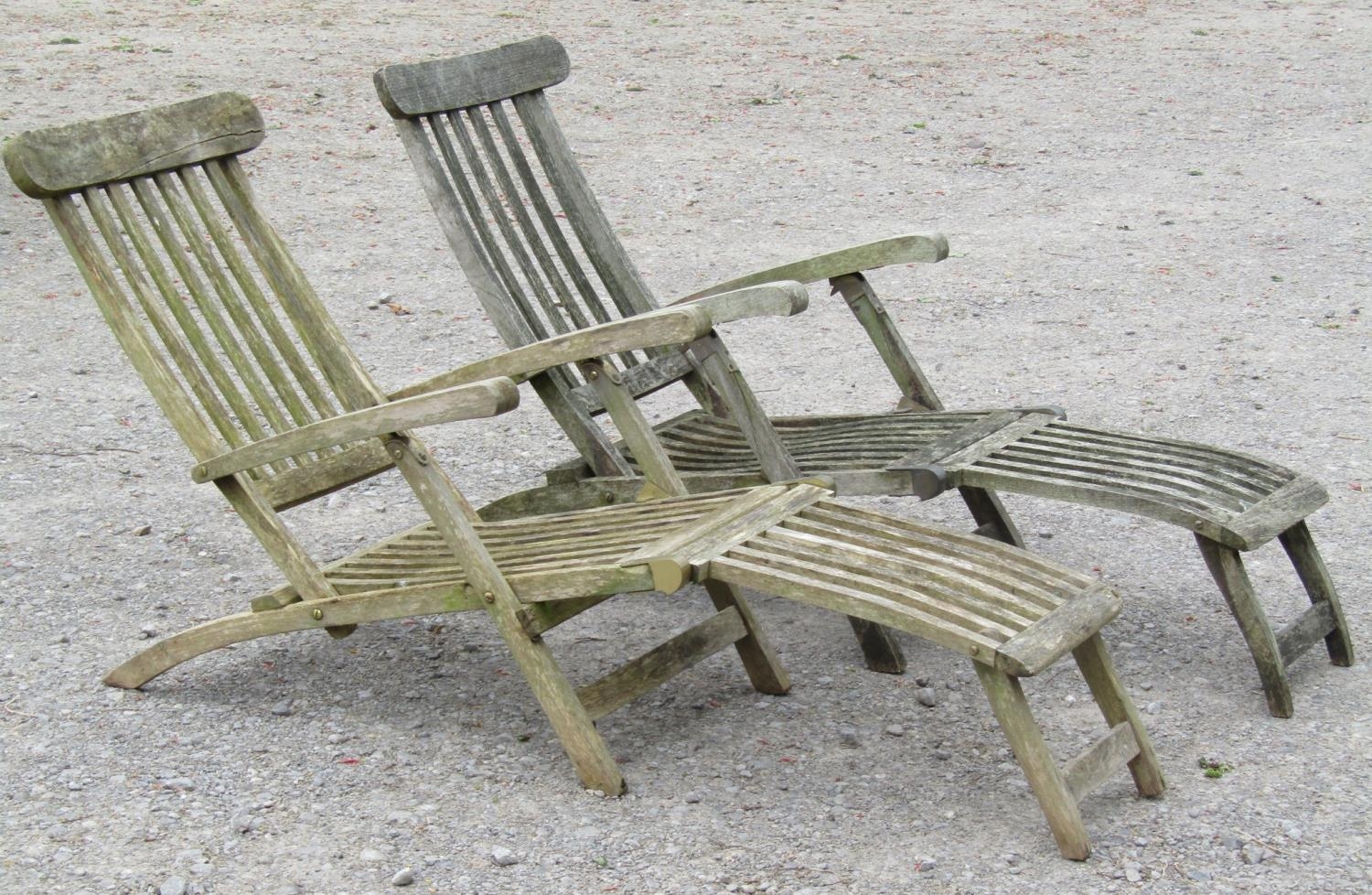 A pair of weathered teak folding garden steamer type lounge chairs with slatted seat, back and