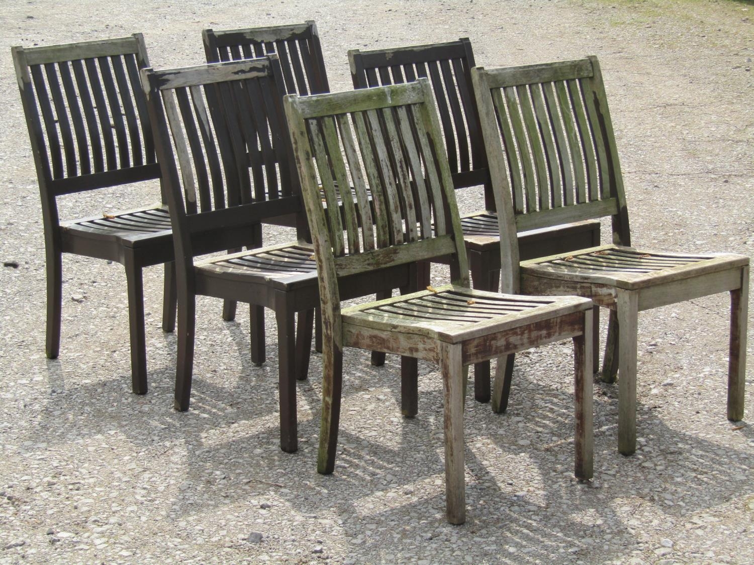 A set of six stained and weathered Gloster teak garden chairs with slatted seats and backs (