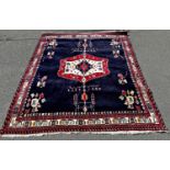 A dark blue Middle Eastern carpet with a central extended stepped medallion, 220cm x 180cm.