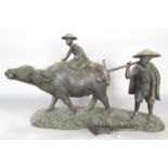 A South East Asian bronze group of a boy riding a water buffalo with his father in attendance, as