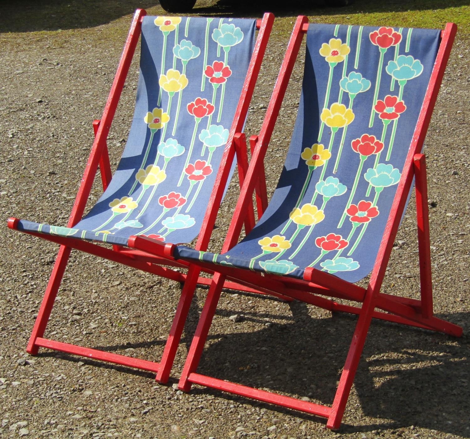 A pair of traditional folding deck chairs with painted frames, floral patterned seats, together with
