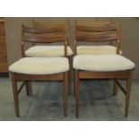 A set of four mid century dining chairs with upholstered seats on turned supports