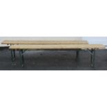 A pair of folding trestle benches with wooden plank seats and folding iron supports, 2 metres long x