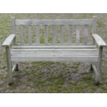 A vintage weathered/silvered teak two seat garden bench with slatted seat and back, probably a