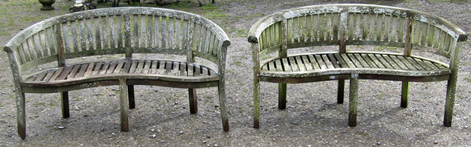 A pair of weathered teak banana shaped garden benches (af) 158 cm wide