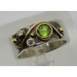 Stylised silver ring bezel set with a peridot and two diamonds, with yellow metal highlights, size