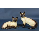 A collection of ceramic cats to include Beswick Siamese casts in various poses, a grey Winstanley