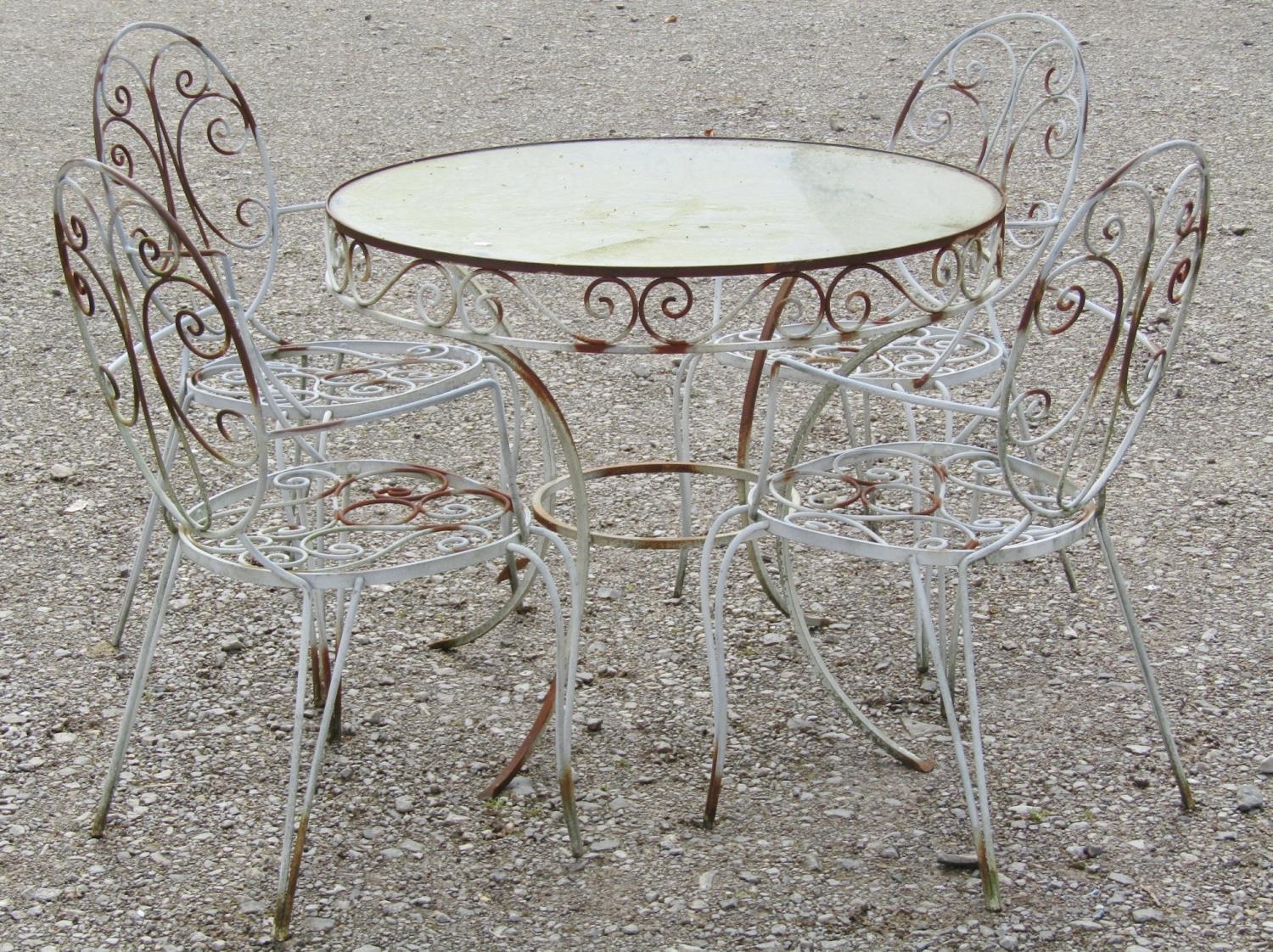 A weathered iron work garden terrace suite comprising circular inset glass top table 92 cm