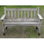 A weathered two seat garden bench with slatted seat and back, 128 cm wide (af)