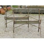 A pair of weathered light steel regency style two seat garden benches with open scrolled arms,
