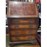 A mid 20th bureau with fall flap enclosing pigeon holes and door, over four drawers with brass