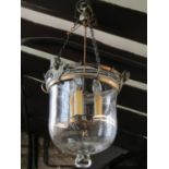 A vintage pendant light with glass dome shade and metal fittings with face mask detail