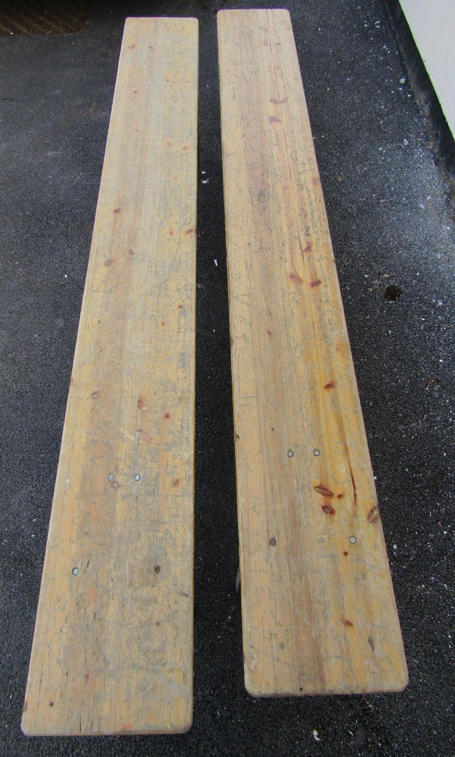A pair of folding trestle benches with wooden plank seats and folding iron supports, 2 metres long x