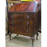 A late Edwardian mahogany ladies writing bureau of three long drawers, the fall flap enclosing a