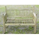 A vintage Arts & Crafts style weathered teak two seat garden bench with slender slatted seat and