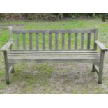 A vintage weathered teak three seat garden bench with slatted seat and back, probably a Lister