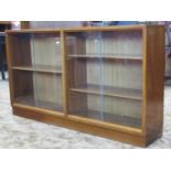 A mid 20th century side by side bookcase enclosed by two pairs of plate glass sliding doors, with