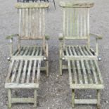 A pair of weathered teak folding steamer type garden lounge chairs with slatted seats, backs and