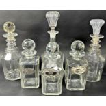 Three square cut glass decanters one with a silver drinks label, Whisky, and three similar decanters
