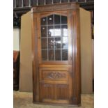 Reproduction oak floorstanding corner cabinet enclosed by two doors, with carved detail