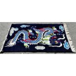 A dark blue Chinese rug with a large single dragon, a pale green Chinese rug with a small central