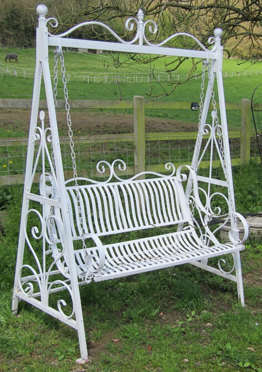 A painted metal two seat garden swing raised on A framed supports with open scroll detail, 154 cm (