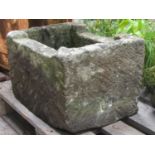 A weathered carved rectangular natural stone trough with cut-out channelled edge and circular