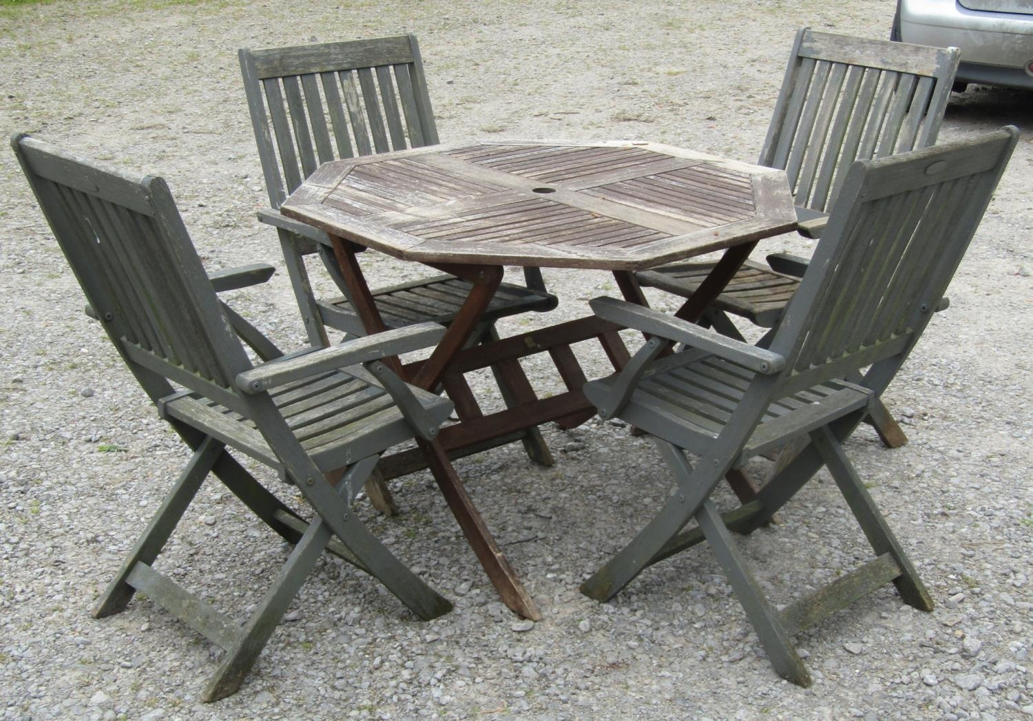 A weathered folding hardwood garden table with octagonal slatted panelled top, together with a set