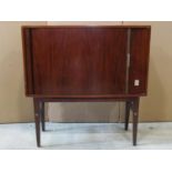 A small mid century side cabinet enclosed by a tambour door raised on stand