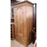 A contemporary pine wardrobe enclosed by an arched and panelled door over a single frieze drawer, 88