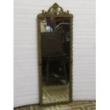 A rectangular gilt framed mirror with repeating leaf detail beneath a scrolling pediment, 102cm